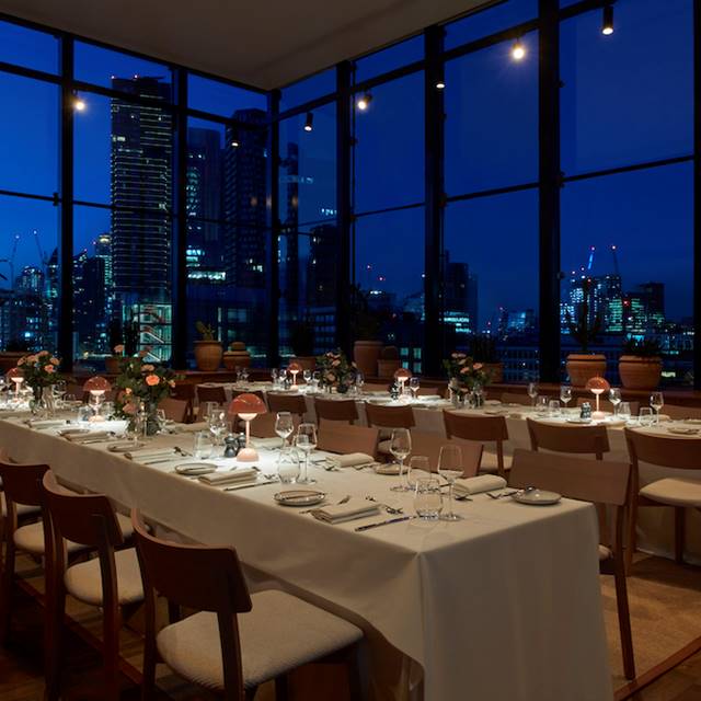 A restaurant featuring a stunning view of the city skyline, showcasing tall buildings against a vibrant sky.