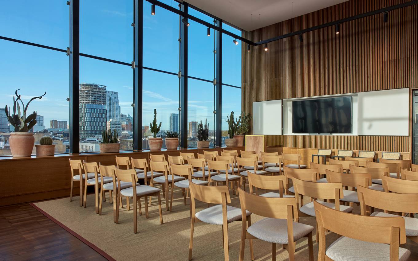 A conference room featuring wooden chairs and a large window allowing natural light to illuminate the space.