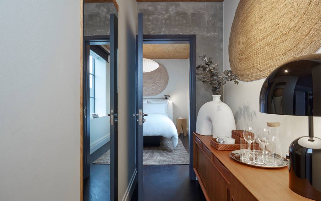 A modern and minimalist London hotel bedroom at One Hundred Shoreditch with white linens, natural decor, and soft lighting.