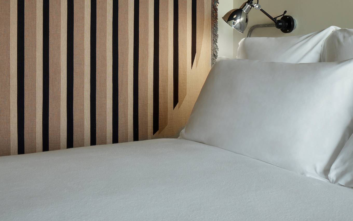 A neatly made bed featuring crisp white sheets and fluffy pillows, creating a serene and inviting atmosphere.