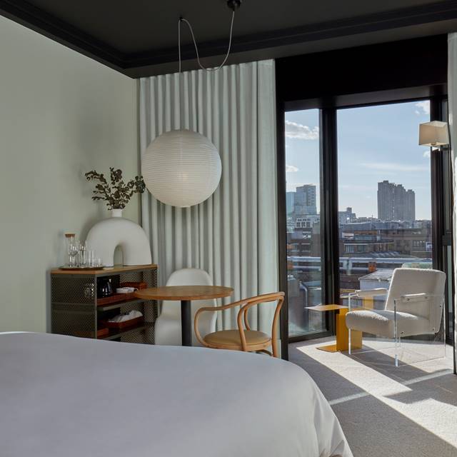 A welcoming bedroom featuring a bed and a stunning view of the city skyline through large windows.