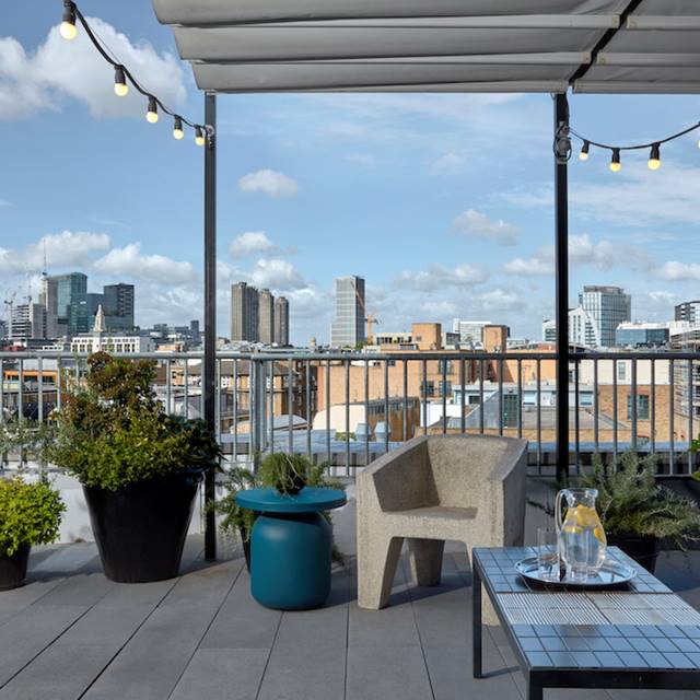 A balcony featuring white furniture, offering a scenic view of the city skyline in the background.