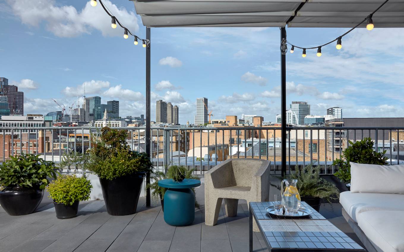 A balcony featuring white furniture, offering a scenic view of the city skyline in the background.