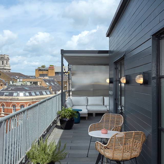 A balcony adorned with wicker chairs provides a picturesque view of the bustling city below.