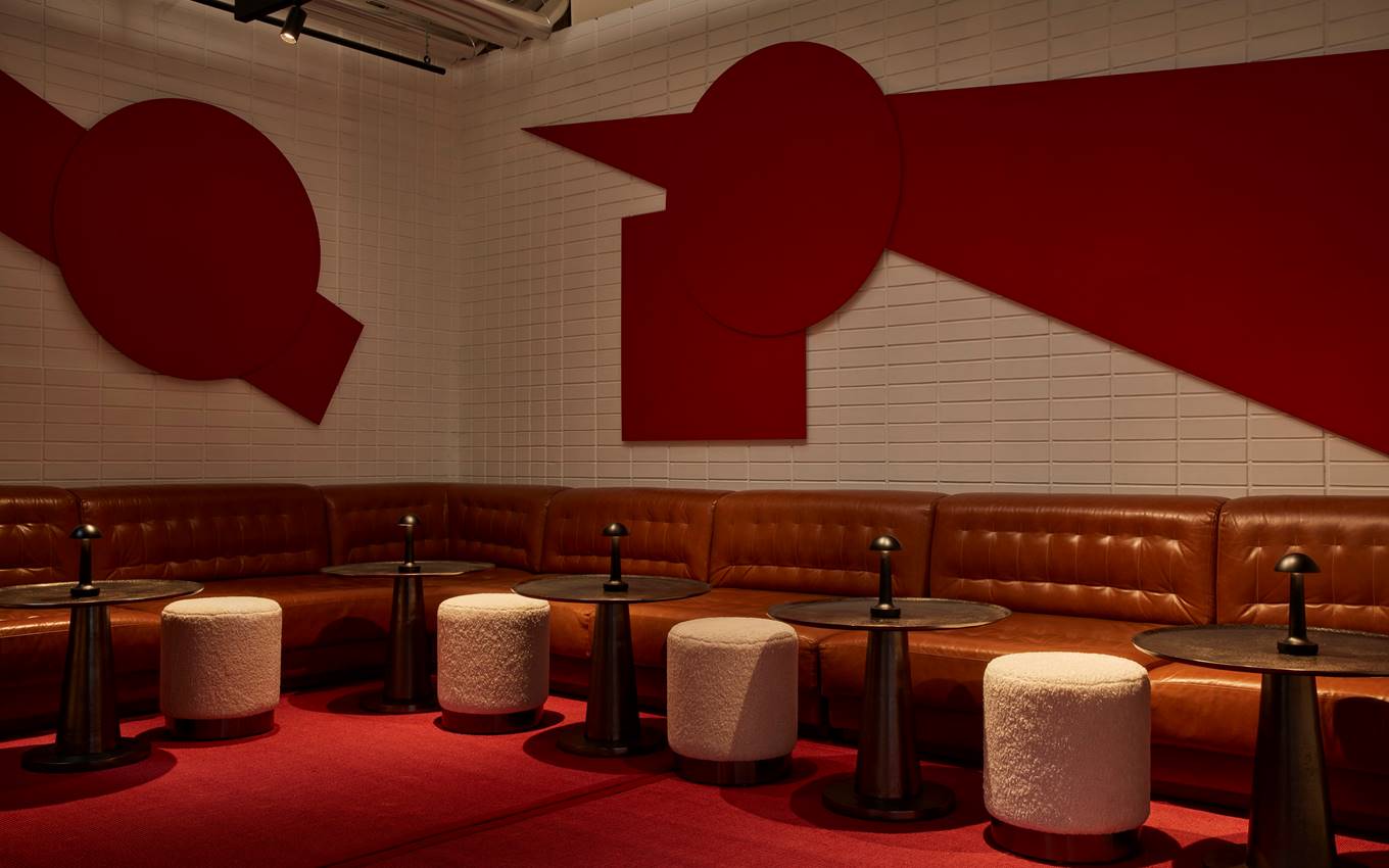 A red and white lounge bar featuring a striking red wall, creating a bold and vibrant atmosphere.