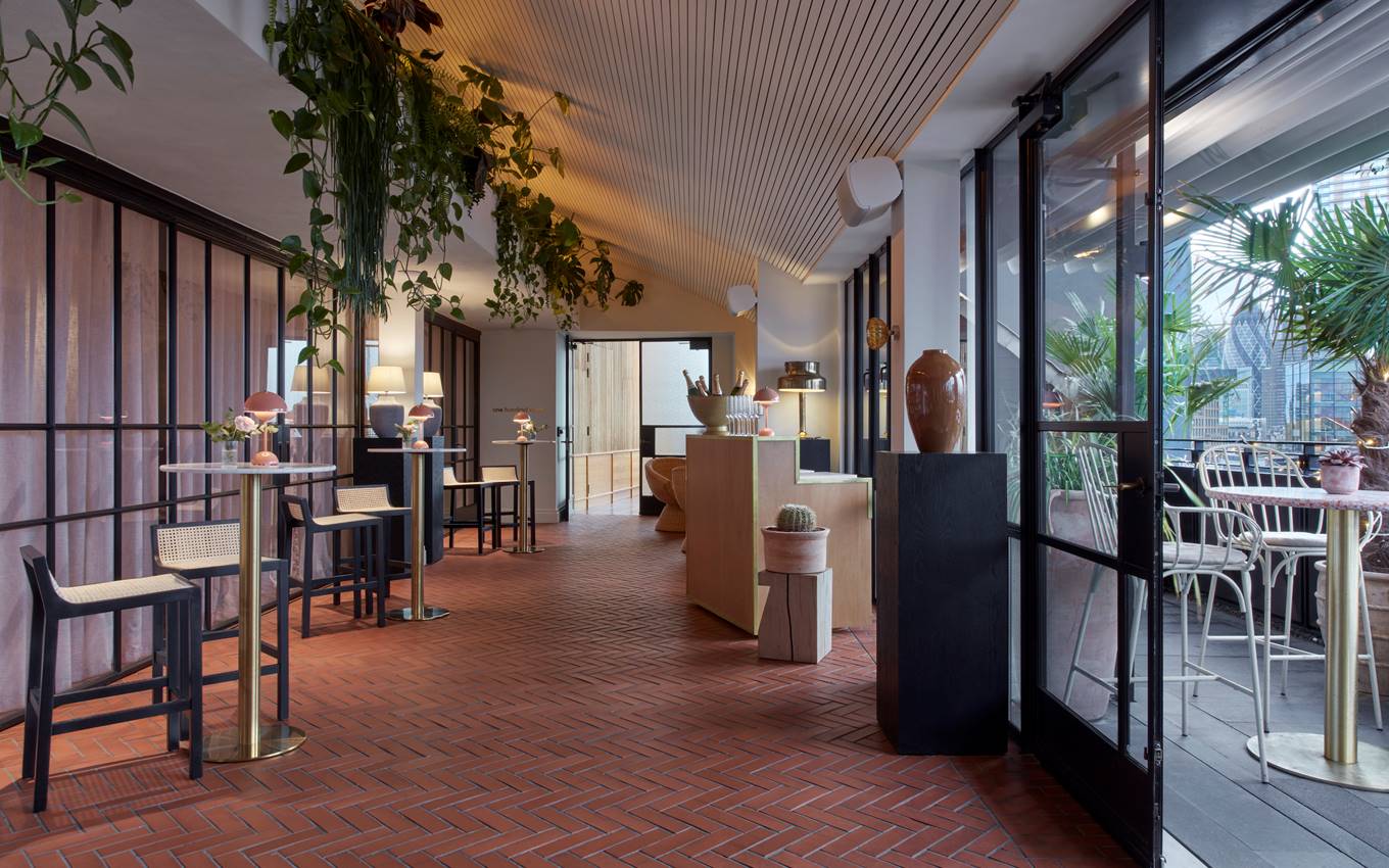 A restaurant featuring a large glass door and an expansive table, inviting guests to enjoy a communal dining experience.