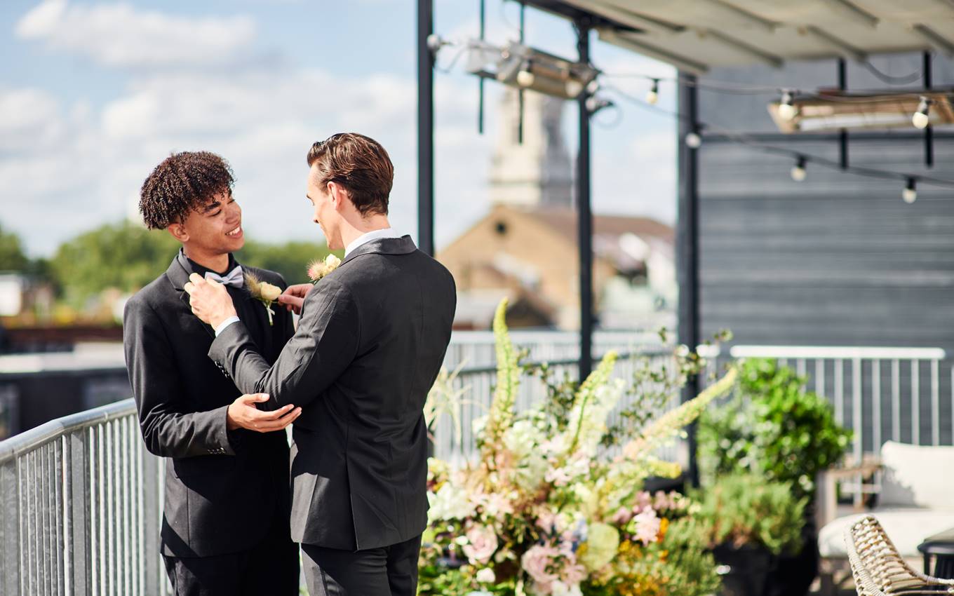 Two men in suits are adjusting their ties, showcasing a moment of preparation and anticipation.