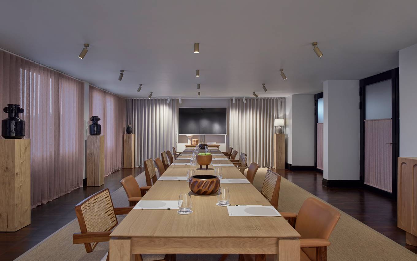 A long table surrounded by chairs, featuring a lamp positioned centrally on the table.