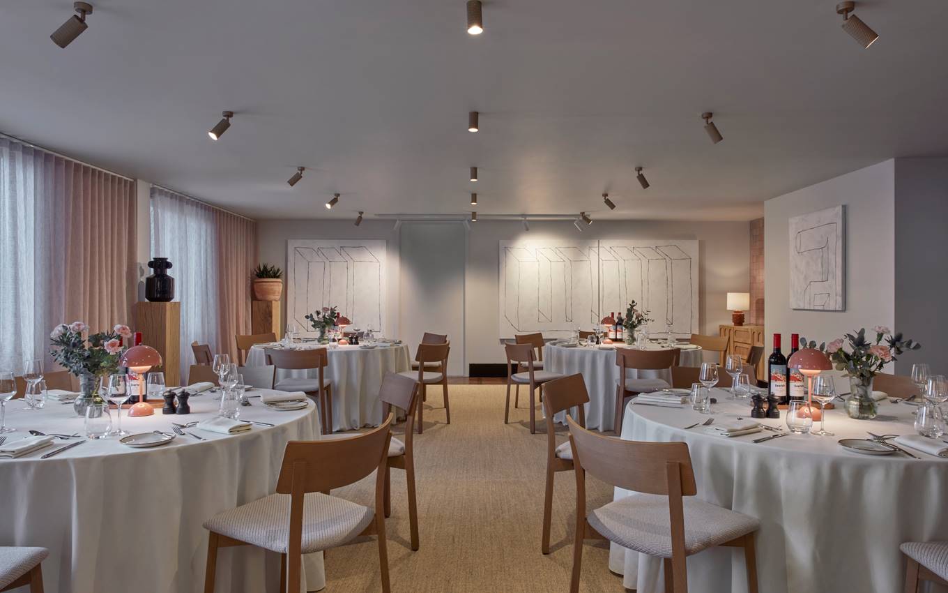 A spacious dining room arranged with tables and chairs, ready for an elegant dinner party setting.