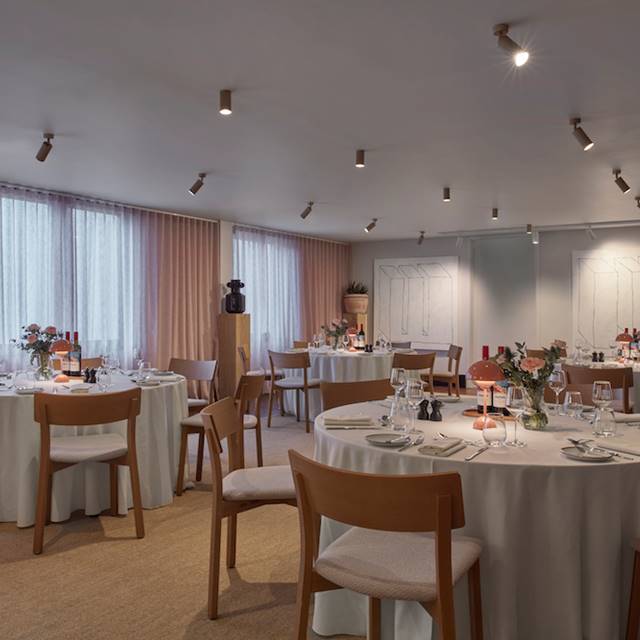 A spacious and light filled dining room featuring multiple tables and chairs arranged for dining.