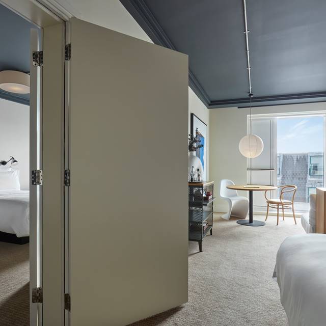 Spacious suite at One Hundred Shoreditch with an adjoining sitting and bedroom area, decorated in minimalist style.