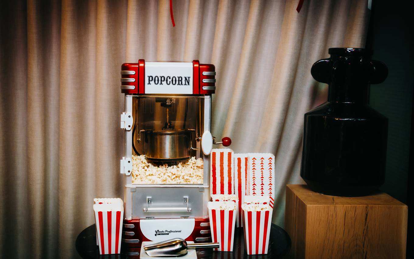 Classic popcorn machine with red and white striped boxes and fresh popcorn, set against a curtain at Curzon Cinema in London.