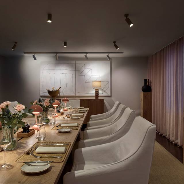 Cosy dining room setup with pink lamps, floral centrepieces, and wall art, creating an inviting atmosphere for guests.