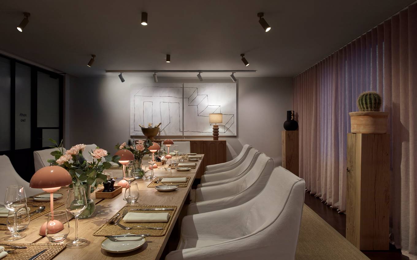 Cosy dining room setup with pink lamps, floral centrepieces, and wall art, creating an inviting atmosphere for guests.