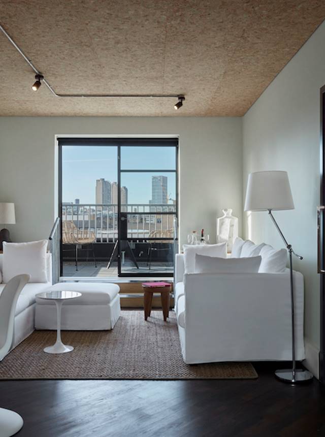 A modern living room featuring white furniture and a panoramic view of the city skyline through large windows.