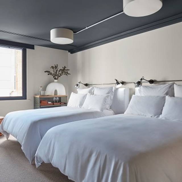 A room featuring two beds with white sheets, complemented by blue walls, creating a serene and inviting atmosphere.