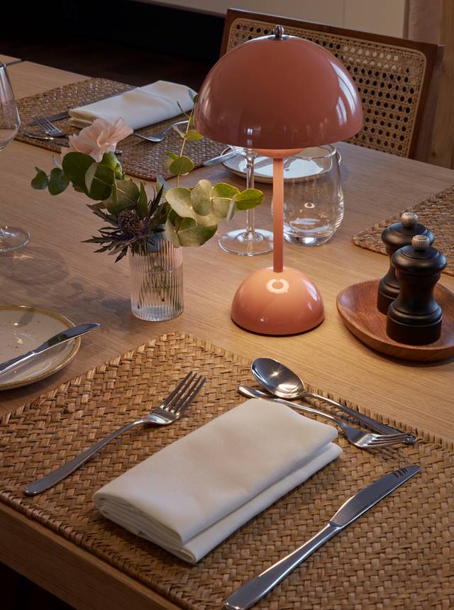 A neatly arranged table featuring a lamp and an elegant place setting, creating a warm and inviting atmosphere.